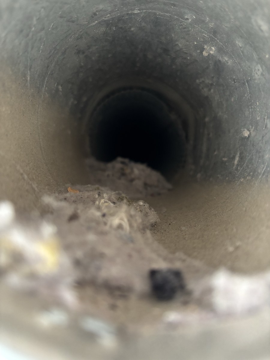 Dryer vent pipe before cleaning, piles of lint inside