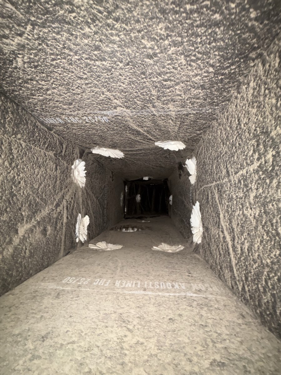 Long lined duct run before cleaning, thick tan dust on every surface