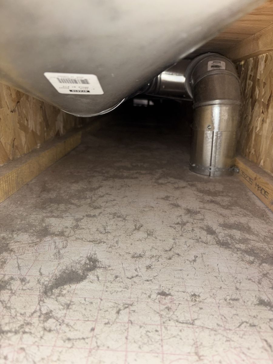 Return air duct in a floor joist bay with dust across the floor before cleaning