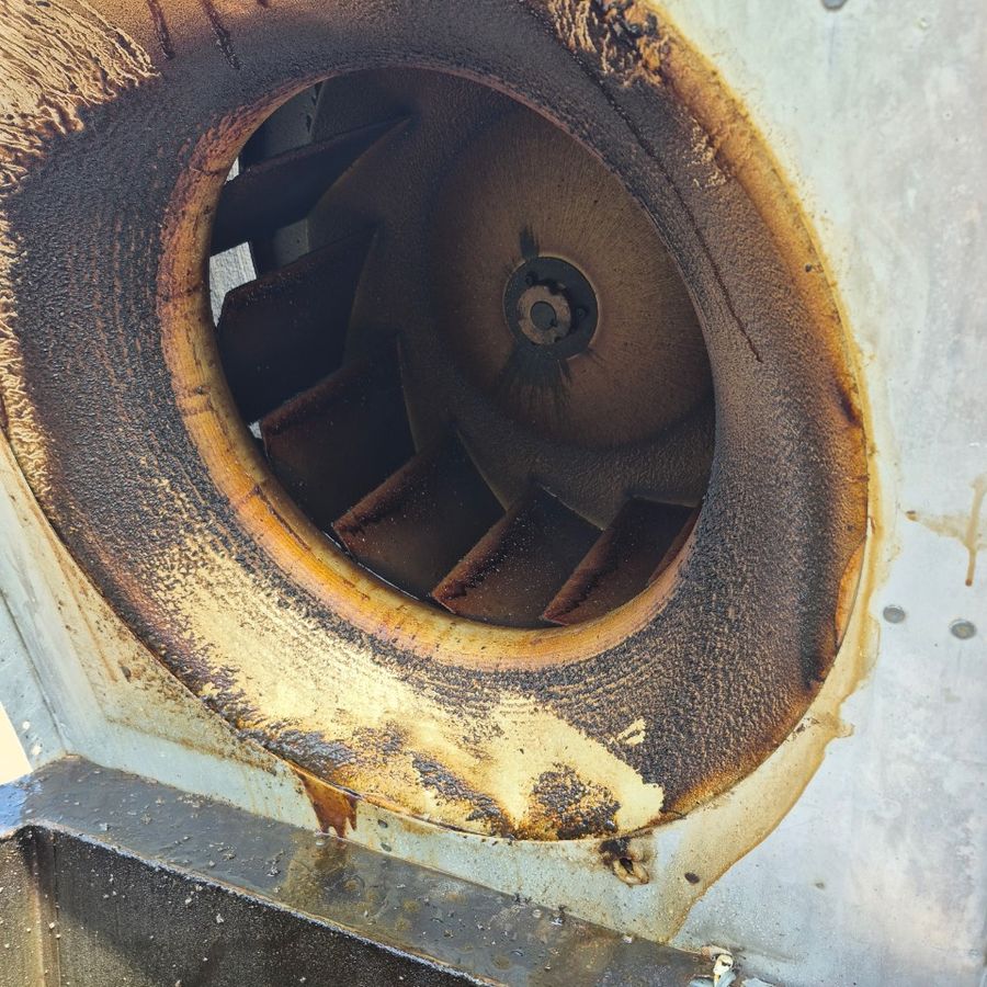 Commercial kitchen exhaust fan with thick black grease around the inlet before cleaning