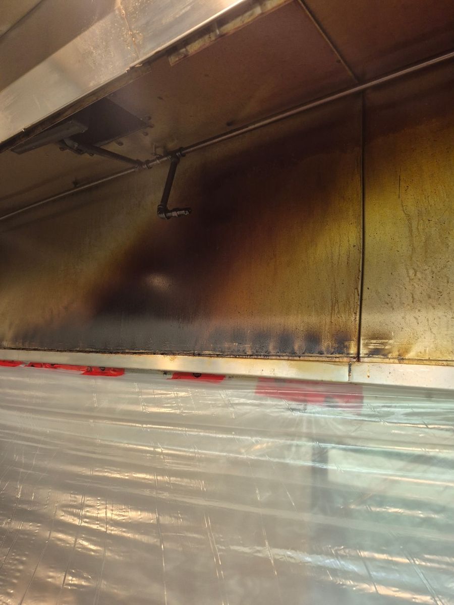 Kitchen hood wall with brown smoke and grease stains before cleaning