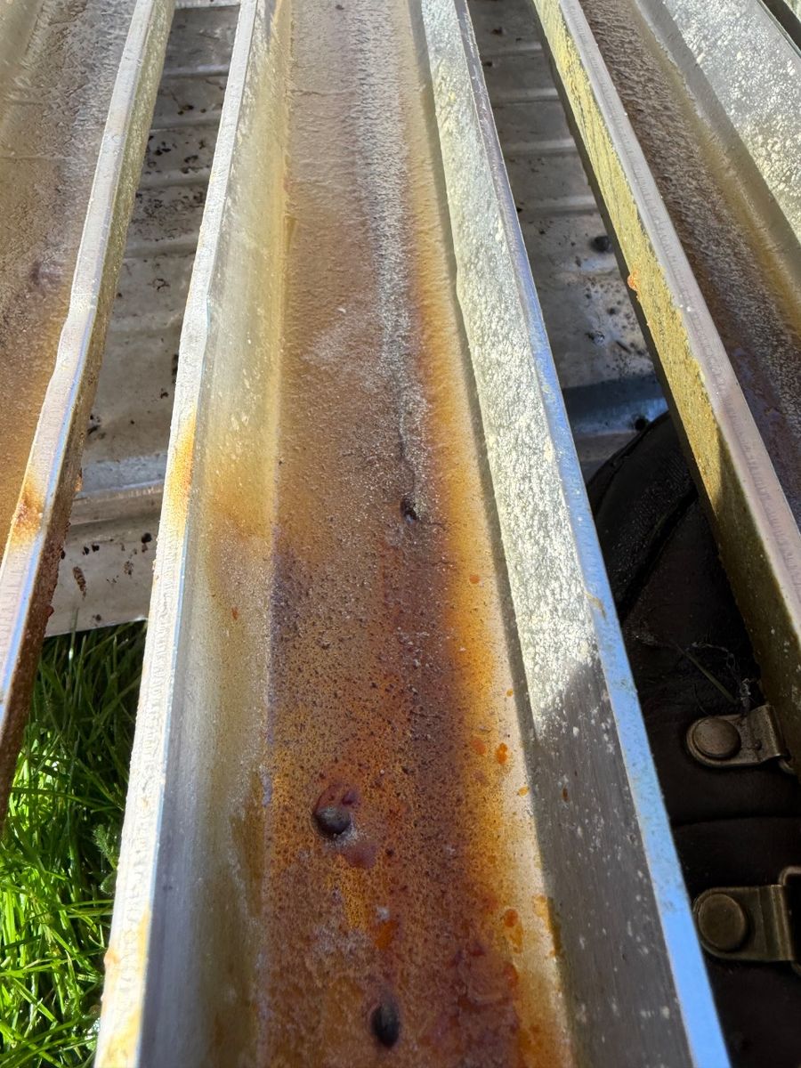 Kitchen hood filter channels with orange-brown buildup before cleaning